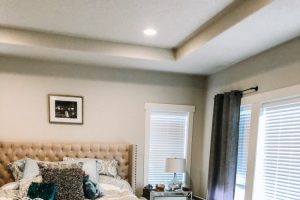 master bedroom with tufted headboard and vacuum lines